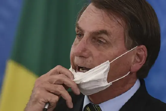 Brazil\\\\\\'s President Jair Bolsonaro removes his mask to speak to journalists after a press conference on the new coronavirus, at the Planalto Presidential Palace in Brasilia, Brazil, Wednesday, March 18, 2019. For most people COVID-19 causes mild or moderate symptoms. For others, especially the elderly and people with existing health problems, it can cause many other serious illnesses, including pneumonia. (AP Photo/Andre Borges)