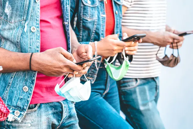 Close up of friends hands with face masks using tracking app on mobile smart phones - Young millenial people sharing content at social media networks - New normal lifestyle concept - Bright filter (Close up of friends hands with face masks using track