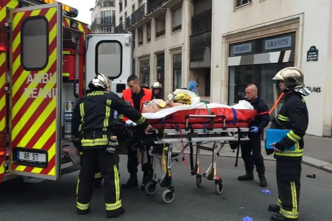 Firefighters carry an injured man on a stretcher in front of the offices of the French satirical newspaper Charlie Hebdo in Paris on January 7, 2015, after armed gunmen stormed the offices leaving at least one dead according to a police source and \"six seriously injured\" police officers according to City Hall. AFP PHOTO / PHILIPPE DUPEYRAT\\r\\n