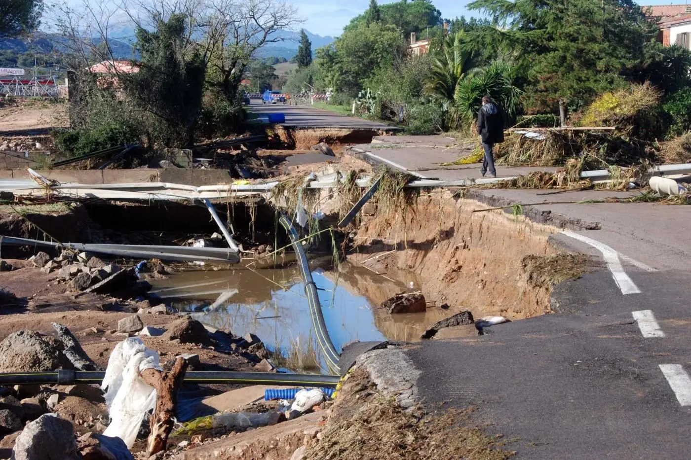 A man walks along a damaged a day after torrential rainstorms battered Sardinia, in Olbia, Italy, Tuesday, Nov. 19, 2013. The Mediterranean island of Sardinia, prized by the jet-set for its white sand beaches and crystal-clear seas, was a flood-ravaged mud bath Tuesday after a freak torrential rainstorm killed at least 17 people, downed bridges and swept away cars. Olbia Mayor Gianni Giovannelli said the city had been destroyed by the &quot;apocalyptic&quot; storm, with bridges felled and water levels reaching 3 meters (10 feet) in some places. He described the ferocity of the storm\\'s rains as a &quot;water bomb.&quot; (AP Photo)