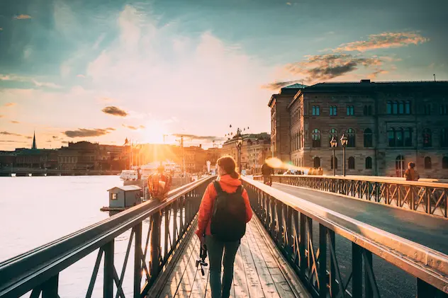 Stockholm, Sweden. Young Caucasian Woman Lady Tourist Traveler Walking On Famous Skeppsholmsbron - Skeppsholm Bridge. Popular Place, Landmark  And Destination In Stockholm, Sweden.