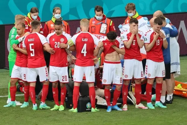 TOPSHOT - Denmark\\'s players gather as paramedics attend to midfielder Christian Eriksen (not seen) during the UEFA EURO 2020 Group B football match between Denmark and Finland at the Parken Stadium in Copenhagen on June 12, 2021. (Photo by WOLFGANG RATTAY / various sources / AFP) (Photo by WOLFGANG RATTAY/AFP via Getty Images)
