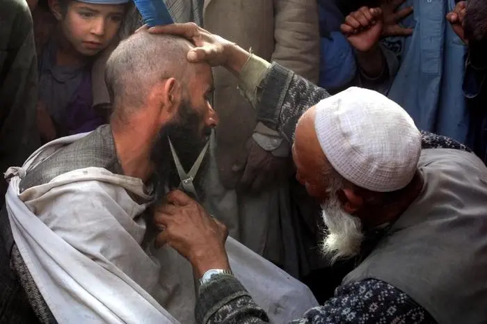 JBL04 - 20011113 - KABUL, AFGHANISTAN : Street hairdresser cuts a  man\\'s beard 13 November 2001 in Kabul, after Northern Alliance soldiers captured the capital.  A few hours after opposition forces poured into Kabul, many men cut their beards as it was forbidden during the Taliban regime. Taliban spiritual leader Mullah Mohammad Omar has fled Afghanistan for Pakistan, RIA Novosti quoted a senior Northern Allliance official as saying Tuesday in neighboring Tajikistan.    ANSA /ALEXANDER NEMENOV/ CD