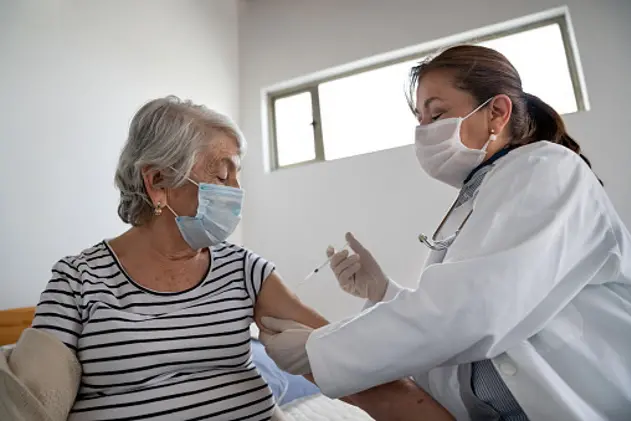 Latin American senior woman getting a COVID-19 vaccine by a doctor at a nursing home \\u00E2\\u0080\\u0093 illness prevention concepts