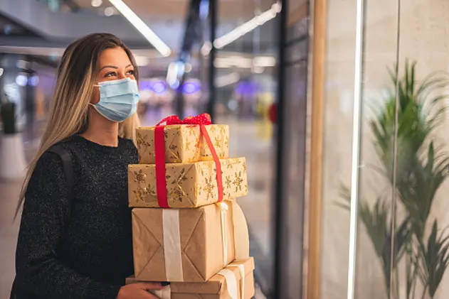 Young beautiful girl walking and shopping Christmas gifts at the mall during the COVID-19 pandemic. She wear a protective mask to protect from corona virus COVID-19.