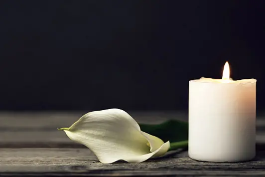 Burning candle and white calla on dark background with copy space. Sympathy card