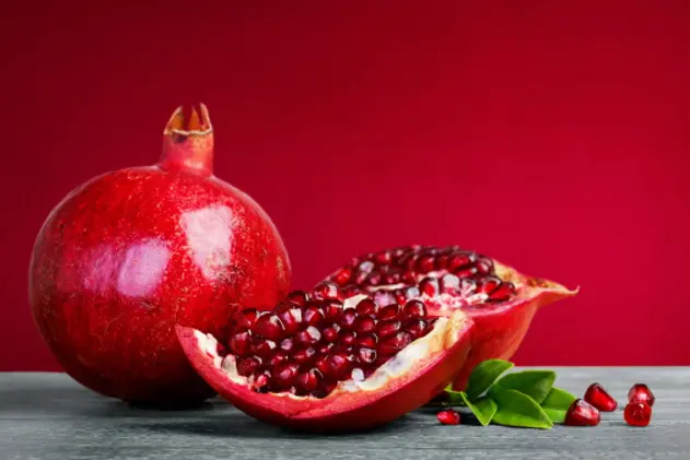 Juicy pomegranate fruit with leaves  on a red background