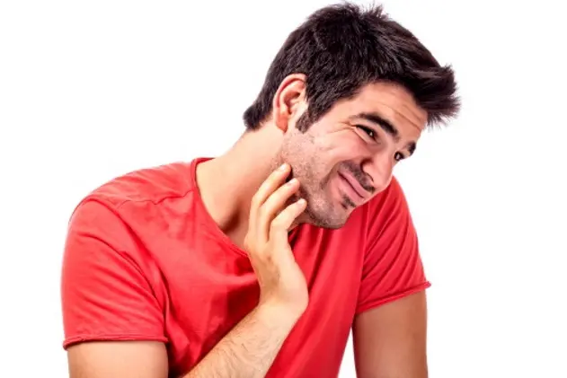 Young man scratching his chin beard as uncomfortable.