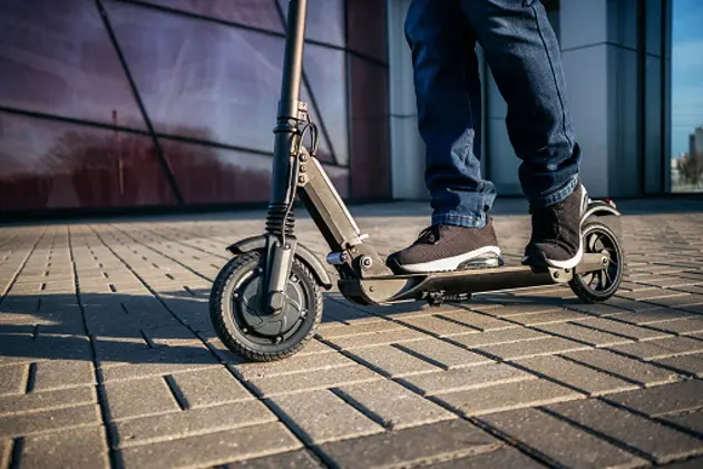 Close up view of legs of man on electric scooter outdoor.