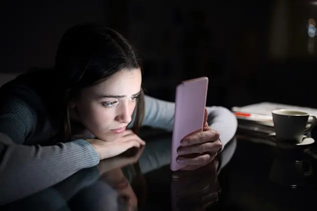 Sad female checking phone content in the night at home