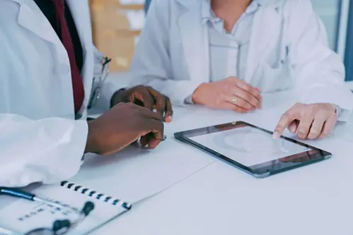 Shot of two doctors using a digital tablet during a discussion in a clinic