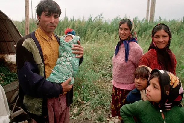 28 Sep 1995, Branesti, Romania --- A group of gypsies stand by a field, en route to their home in Calarasi. A man holds a six-week baby in his arms. --- Image by \\u00A9 Barry Lewis/CORBIS