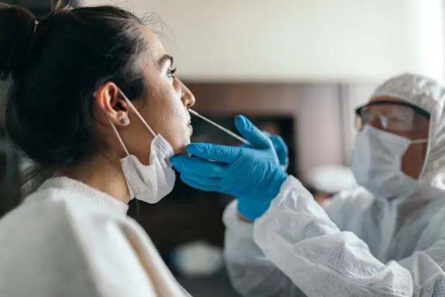 Doctor in protective workwear taking nose swab test from young woman