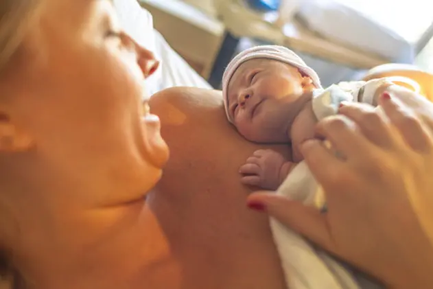 Mother with newborn baby son lying in bed