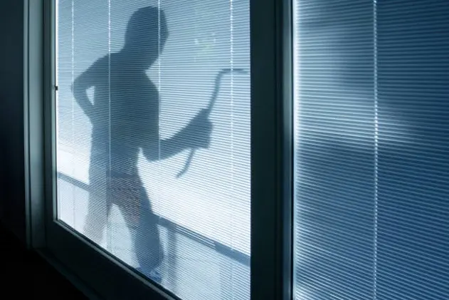 Burglar wearing a balaclava looking through the house window