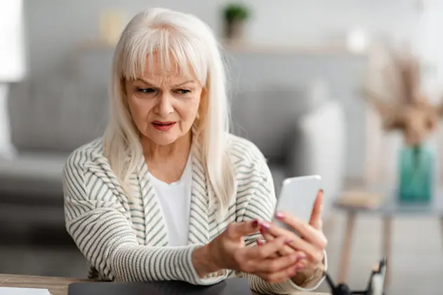 Suspicious Sms. Worried mature woman looking at smartphone screen, received bad news, got fishy scam message, doubtful confused lady holding gadget with concerned face expression, free copy space