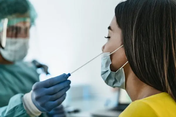 Medical worker wearing personal protective equipment doing corona virus swab on female patient - Covid19 test and health care concept