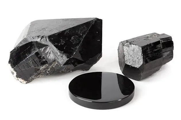 Three black stones: black quartz crystal, black tourmaline crystal and black obsidian mirror.