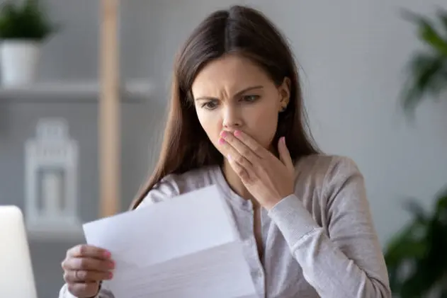 Shocked stressed young woman reading document letter from bank about loan debt financial problem, frustrated worried about bills notification, troubled with bad news or failed test results in mail