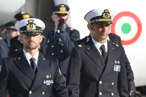 Italian marines Massimiliano Latorre ( R ) and Salvatore Girone ( L ) arrive at Ciampino airport near Rome, on December 22, 2012.An Indian court allowed two Italian marines awaiting trial for shooting two fishermen to go home for Christmas, despite prosecution fears that they will not return. The marines shot dead the fishermen off India\\'s southwestern coast near the port city of Kochi in February while guarding an Italian oil tanker, but they deny murder on the grounds that they mistook their victims for pirates. AFP PHOTO/ VINCENZO PINTO        (Photo credit should read VINCENZO PINTO/AFP/Getty Images)