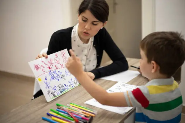 Five years old boy drawing at the psychotherapy session.