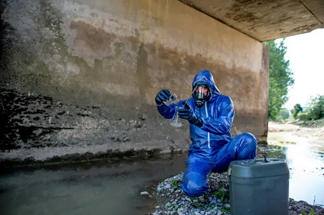 Adult men wearing protective workwear and analyzing sewage water.