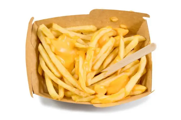 French fries box, fried potatoes french fries with yellow cheese or sauce in brown box isolated white background top view with clipping path.