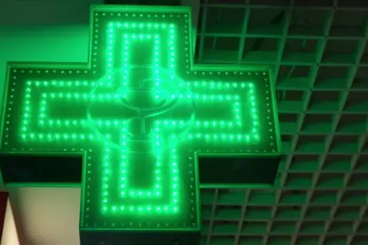 Green cross indicating the location of a pharmacy. Pharmacy Street Sign.