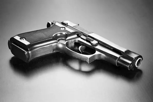 Dimly lit pistol on wooden desk