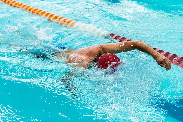 Young and healthy man swimming in an olympic pool. Man swimming very fast, frozen scene