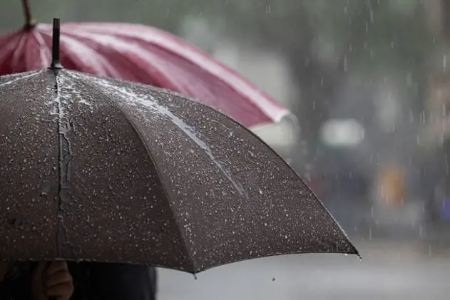 Particular view of a wet grey and red umbrellas after the rain