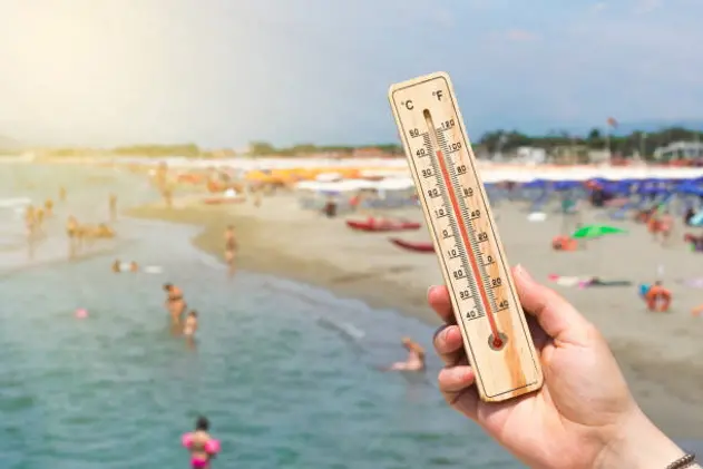 Woman hold a thermometer in front of a crowded Italian beach