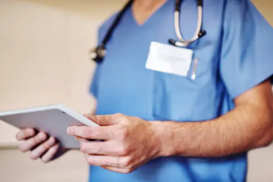 Shot of an unrecognizable doctor using his tablet in his office