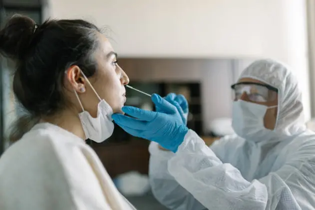 Doctor in protective workwear taking nose swab test from young woman