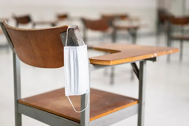 A used medical facemask hangs on a wood lecture chair in the empty classroom during the COVID-19 pandemic