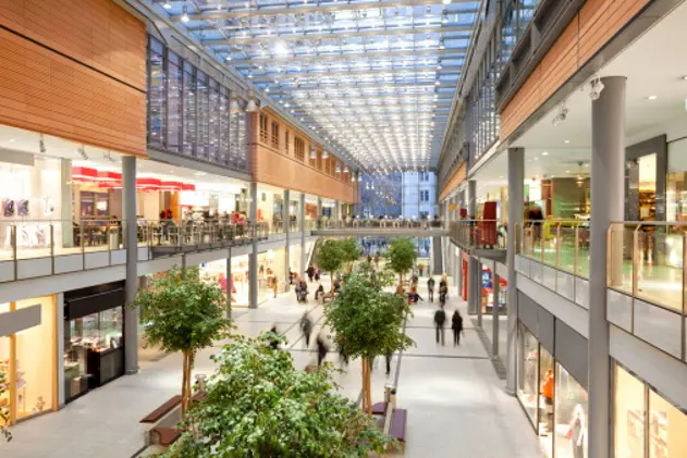 Image taken inside a shopping mall. There are lots of people walking around going to stores, buying things and consuming food and beverages. There are two floors with shops and boutiques. The ceiling is glass. The architecture is very modern and new and the general feel of the images is bright, clean, safe and positive.