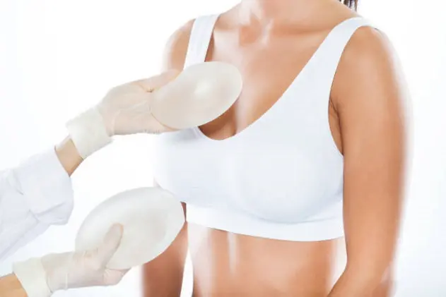 Portrait of female doctor choosing mammary prosthesis with her patient over white background.