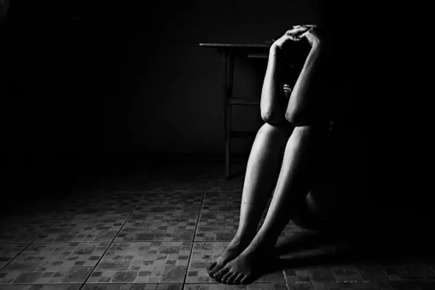 a woman sitting on ground with arm around lower head, sexual violence , sexual abuse, human trafficking concept with shadow edge in white tone