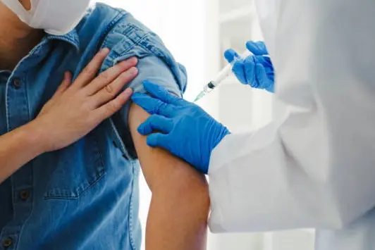 Young Asia lady doctor giving Covid-19 or flu antivirus vaccine shot to senior male patient wear face mask protection from virus disease at health clinic or hospital office. Vaccination concept.