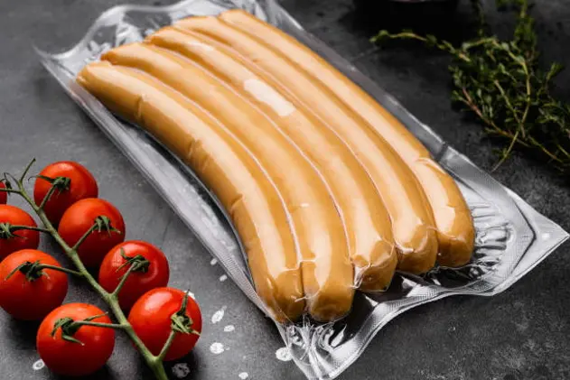 Raw sausages from turkey meat in vacuum pack set, on black dark stone table background