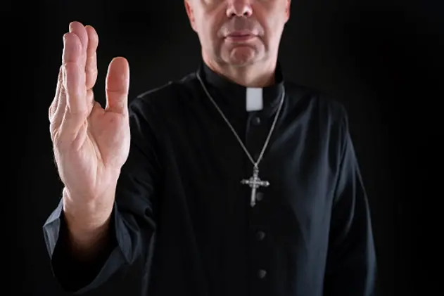 Priest blessing hand with cassock in dark black background