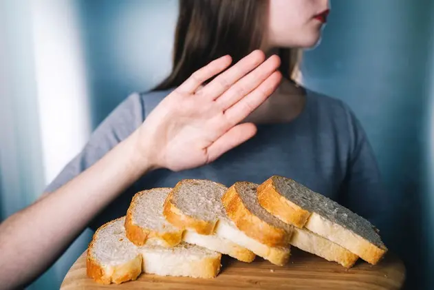 Gluten intolerance concept. Young girl refuses to eat white bread - shallow depth of field - selective focus on bread