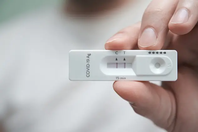 Close-up of a hand holding a positive antigen test for COVID-19. SARS-CoV-2 antigen rapid test kit.