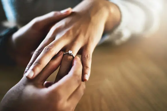 Cropped shot of a man putting an engagement ring onto his girlfriend\\'s finger