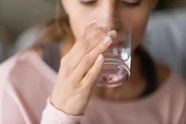 Healthy thirsty young woman holding glass in hand drinking fresh clean pure mineral water at home, dehydrated girl keep hydration balance for body health beauty, hydrate thirst concept, close up view