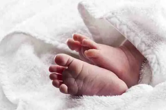 Bare baby feet wrapped in a white towel