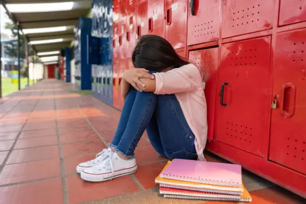 Sad girl at the school sitting on the floor crying about being bullied - lifestyle concepts