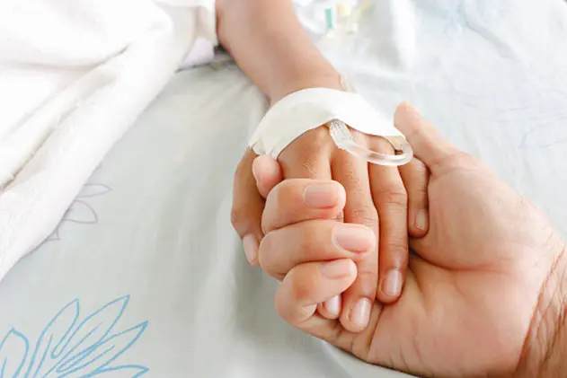 mother holding child\\'s hand who fever patients have IV tube.