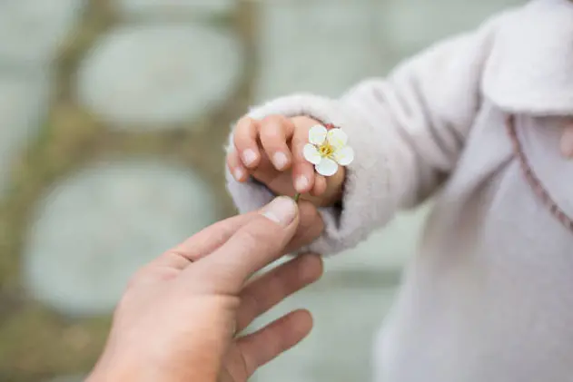 Parent and child handing small white flowers