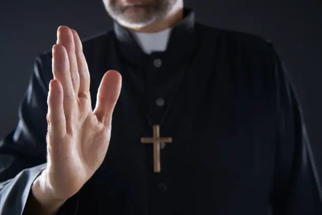 Priest hand blessing closeup with cross and clergyman background